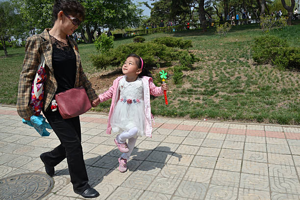 Pyongyang, North Korea - May 1, 2019: Happy little girl with her mother on the Pyongyang street