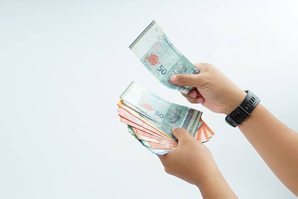 istock Hand holding Malaysian ringgit banknote on white background representing cash payment, personal finance, income, and financial transaction with clean minimal composition. 2254071661