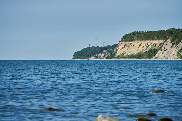 Tranquil seaside landscape with lush green cliff meeting gentle blue sea. Calm waters evoke peace and introspection, while horizon offers endless possibilities