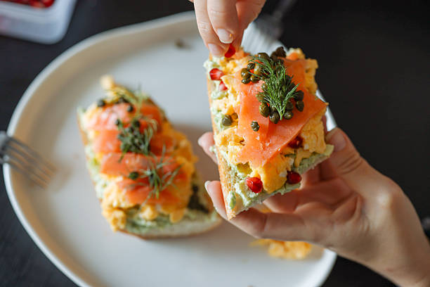Smoked salmon canapes on a brown wooden plate. Delicious avocado and smoked salmon toasts on a rustic wood table top.