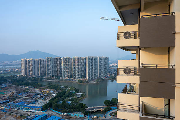 A panoramic view of an urban skyline featuring high-rise buildings and residential complexes, with a river running through the cityscape. The image captures the contrast between modern architecture and natural elements, evoking a sense of bustling city life.