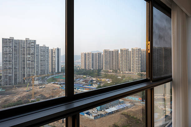 A serene cityscape visible through a window with decorative glass and white curtains, suggesting modern urban living.