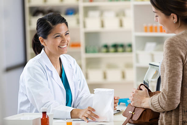 istock Pharmacist assists customer, smiling warmly while handing over a white paper bag. 2254078142
