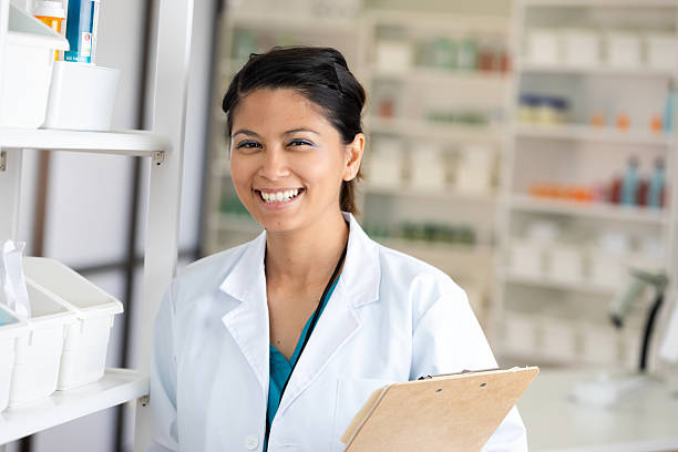 istock Smiling woman in a white lab coat holding a clipboard in a pharmacy setting. 2254078143