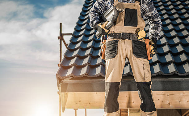 istock Worker on Rooftop Checks Tools While Standing on a House Under a Blue Sky 2254079142
