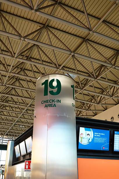 Lombardy, Italy, December 2025: Striking architectural view of Check-In Area 19 pillar in Milan Malpensa Airport Terminal 1, featuring expansive steel truss ceiling, digital flight displays, and modern departure hall ambiance.