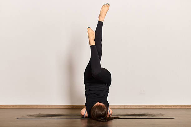 istock Woman practicing shoulder stand yoga pose in bright studio 2254080809