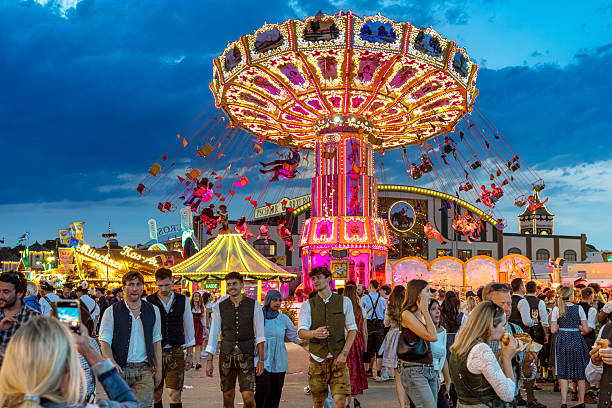 Vibrant night scene of a crowded Munich festival with a giant illuminated carousel, colorful lights, and traditional Bavarian attire creating a lively, festive atmosphere.