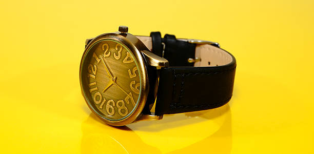 istock Elegant brass watch with black leather strap isolated on yellow background copy space 2254087735