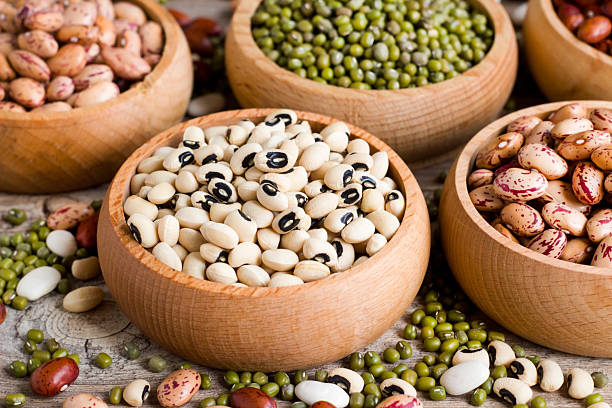 Close-up of black-eyed pea or cowpeas in bamboo bowl with other beans on wooden surface