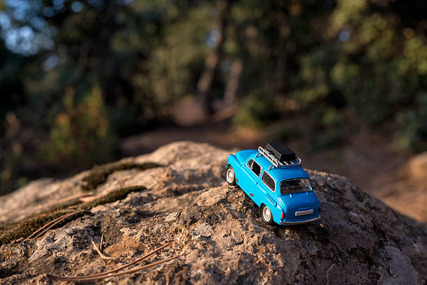 Perranporth, UK - 1st August, 2022:  A beaten and battered VW Beetle sits on a beach in Cornwall with the summer sunshine beating down on its faded paintwork. Scale model photography.