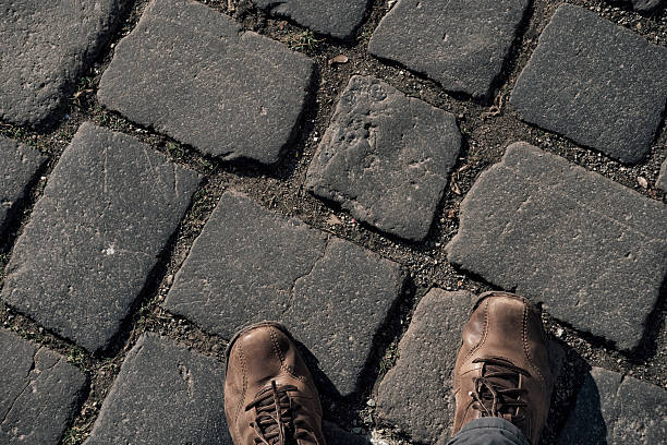 View from above on brown boots on cobblestone pavement background.