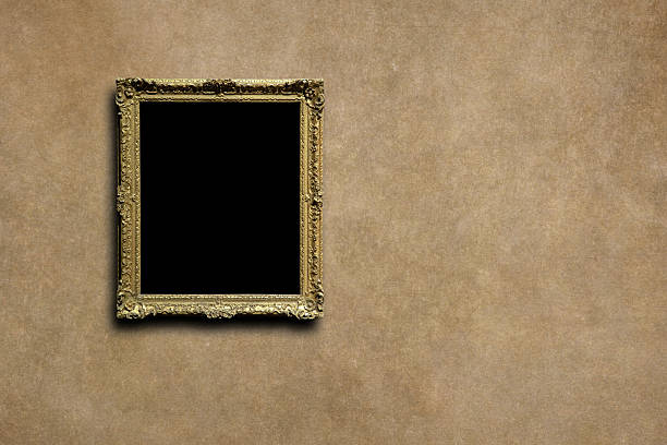 This elegant antique gold picture frame with intricate carvings hangs against a rustic textured wall, offering a perfect blank canvas for your art or message in a classic gallery setting. It evokes a sense of history and sophistication suitable for museum displays.