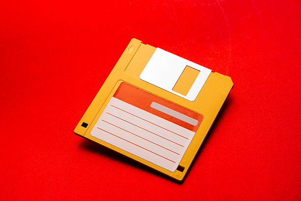 Hand holding a floppy disk with blank label on pink background