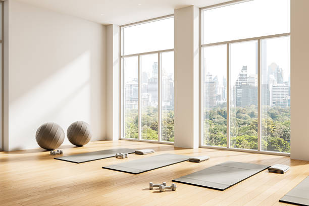 istock Bright yoga studio interior design with large windows, scenic city view, exercise mats, dumbbells, and fitness balls on wooden floor. 3D Rendering 2254098366