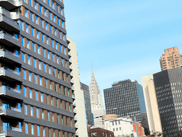 Low angle cityscape view looking up at modern and historic high rise buildings in New York City against a clear blue sky, showing architectural details and strong geometric lines.​Suitable for projects about New York tourism, urban architecture, real estate, financial district, city lifestyle, travel blogs and editorial features highlighting Manhattan skyscrapers and skyline textures.​