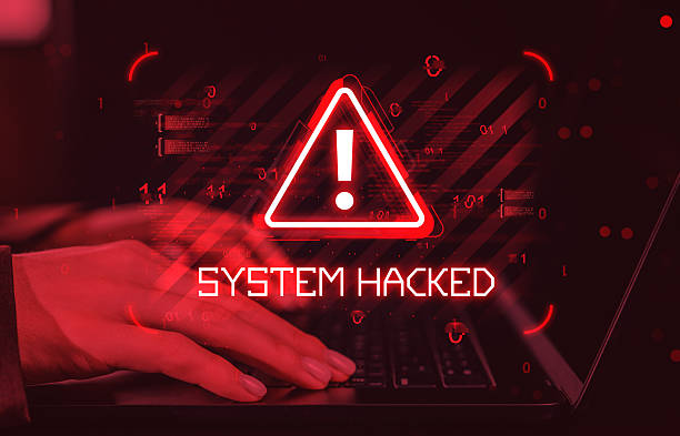 istock System hacked warning alert with glowing red triangle exclamation symbol and hands typing on keyboard in cyber attack concept on dark digital background. 2254098499
