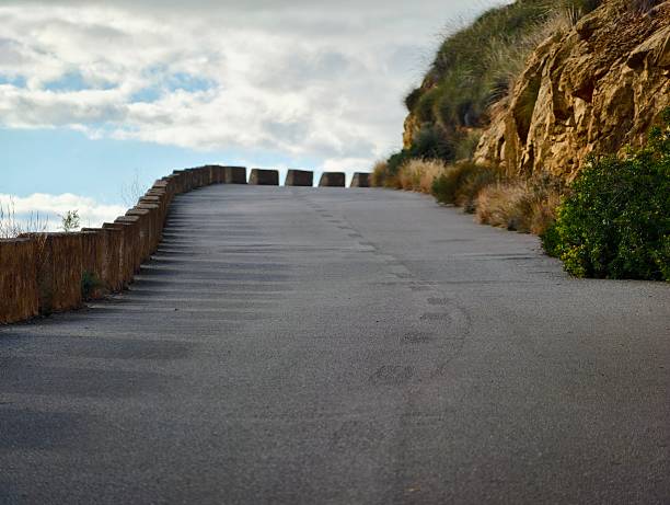 istock Calm coastal route suitable for cycling, Tranquil coastal road beneath brooding cloudy sky 2254100774