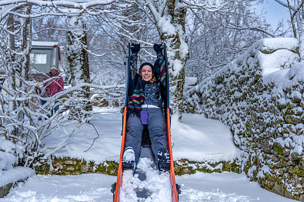 Family tobogganing down a snowy hill during winter vacation