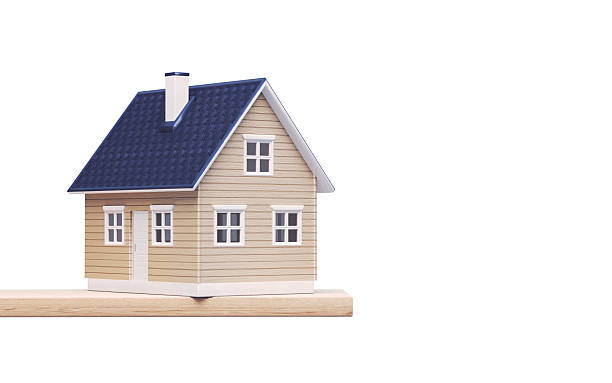 3d render A detailed miniature wooden house model with a blue roof, placed on a wooden base and isolated on a white background. Ideal for concepts related to real estate, property investment, home ownership, mortgage, housing market, architecture, and residential design. Real Estate Buying and Selling Concept