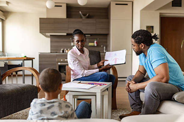 A family consults with a financial advisor in their living room, discussing important documents.