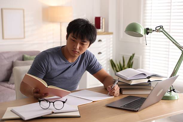 istock Student with laptop and books preparing for exam at table indoors 2254108555