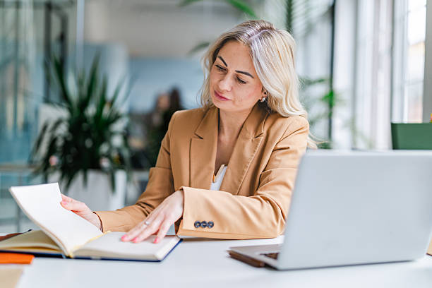 istock Businesswoman engaged in work at office desk while reviewing documents in a bright, modern workspace 2254109967