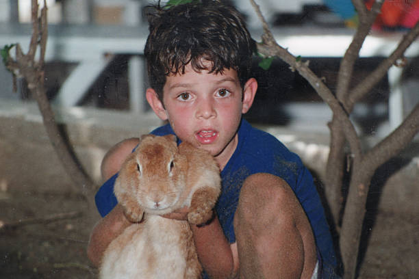 Image taken in 1980s: Little boy holding a rabbit looking at the camera