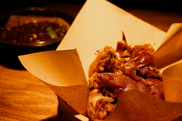 A glossy, braised pork trotter rests on a plate, its deep red-brown skin glistening with savory Guizhou street food marinade.