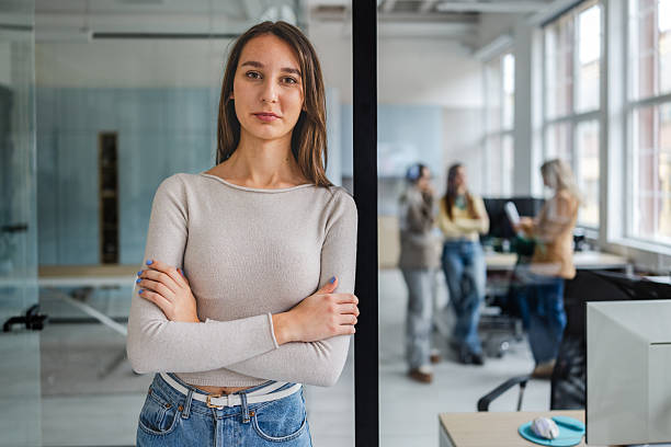 istock Businesswoman stands confidently in office while team collaborates in background during work hours 2254110834