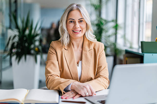 istock Businesswoman working in a modern office setting while smiling and looking at the camera during a productive workday with colleagues 2254112113