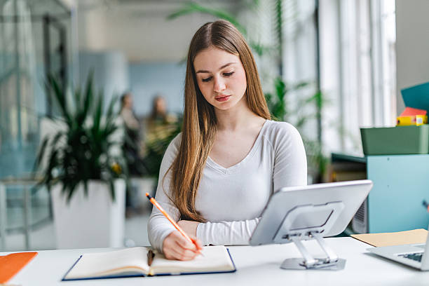 istock Businesswoman writes in notebook while working in modern office environment with colleagues during the day 2254113989
