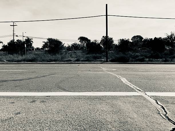 A tar-filled crack in the road pavement leads the eye toward a utility pole in San Marcos, California.