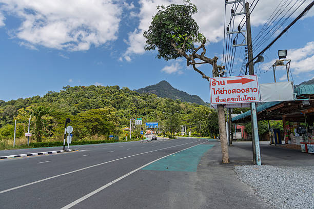 istock road in thailand with directional sign, surrounded by greenery and mountains 2254119542