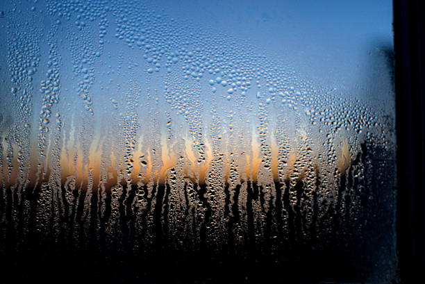 Dew or rain drops flowing down the glass against the backdrop of a beautiful sunrise