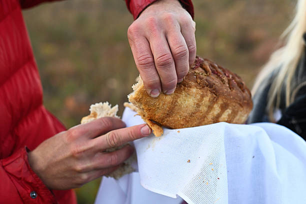 Closeup of hands sharing pie outdoors on white cloth. loaf being broken into pieces shows soft crumb. Natural lifestyle food scene, rustic baking tradition. hands tearing homemade pie. homemade bread.