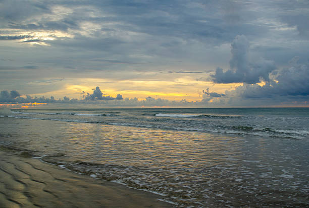 Sunset over the sea with dramatic cloud contrast and shimmering highlights across rolling waves, Kuala Penyu, Sabah, Malaysia