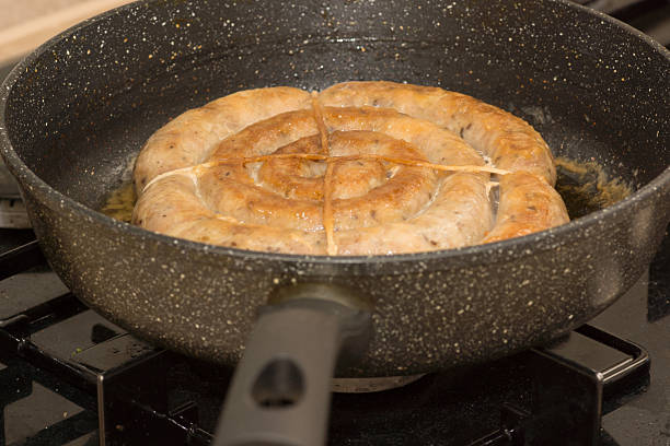 Delicious sausage tied with twine is fried in a frying pan