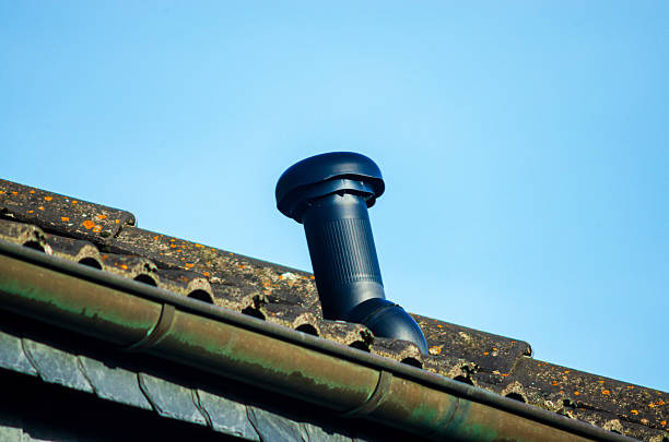 istock Black ventilation pipe on a weathered roof against a clear blue sky 2254137158