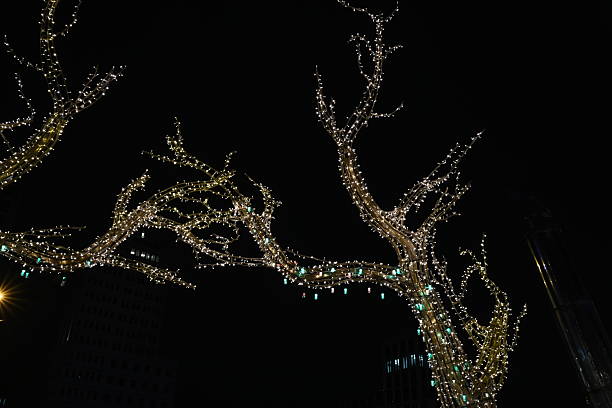 Golden LED lights on a tree-shaped decoration at night. Festive holiday illumination for city streets and Christmas celebrations.