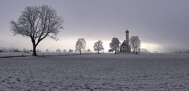 The pilgrimage church of St. Coloman in winter with the mountains behind it