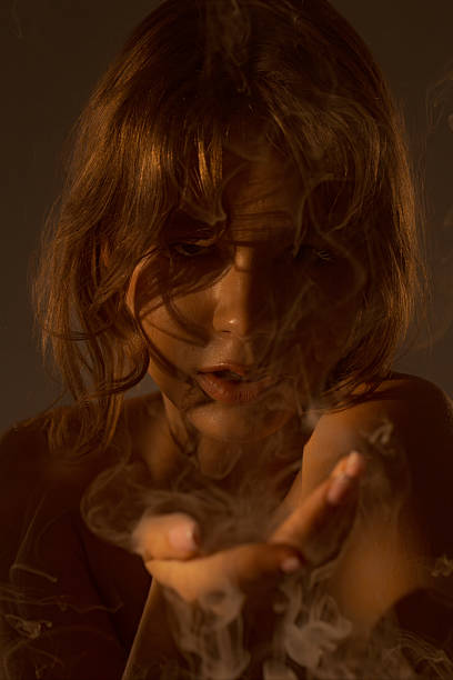 istock Mysterious Woman Blowing Smoke in Low Light 2254140299