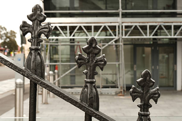 Wrought iron fence detail with a building under construction in the background.