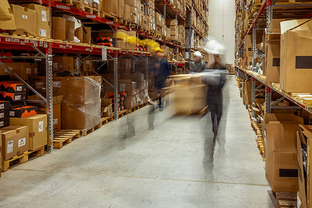 istock Warehouse Workers in Motion Blur Pushing Pallet Jacks Through Distribution Center Aisles 2254143426