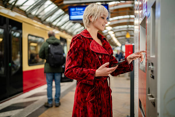 istock Young woman using a ticket machine at a train station in Berlin while waiting for a train 2254143872