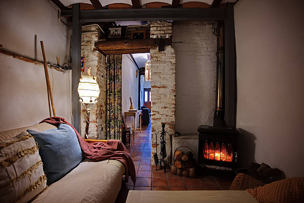 A warm, inviting living space featuring a wood stove, brick pillars, soft textiles, and ambient lighting. Perfect for themes of home, comfort, and rustic charm.