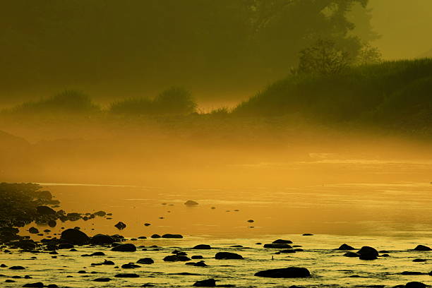 Silhouette of a man standing in a river fly fishing at dusk.