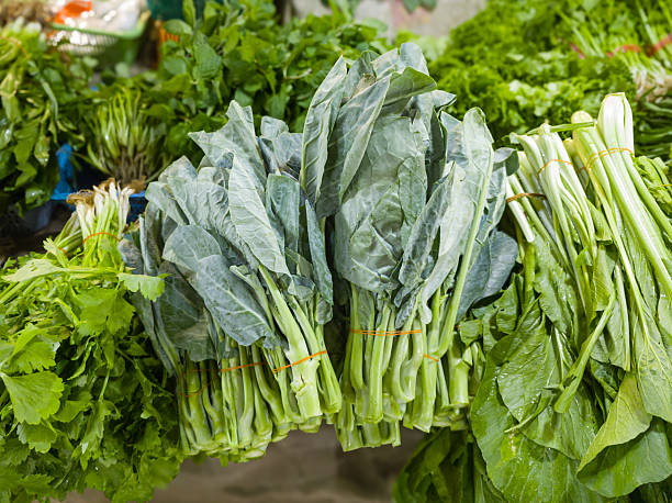 Close-up of fresh kale and assorted leafy vegetables displayed at market. Perfect for food, cooking, and healthy themes.