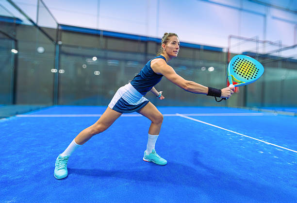 istock Determined female padel player in action performing a low backhand stroke on a blue indoor court. 2254149104
