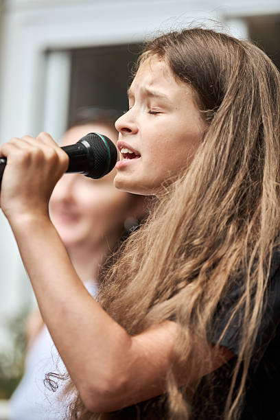 istock Young girl singing passionately into microphone during outdoor event 2254151817